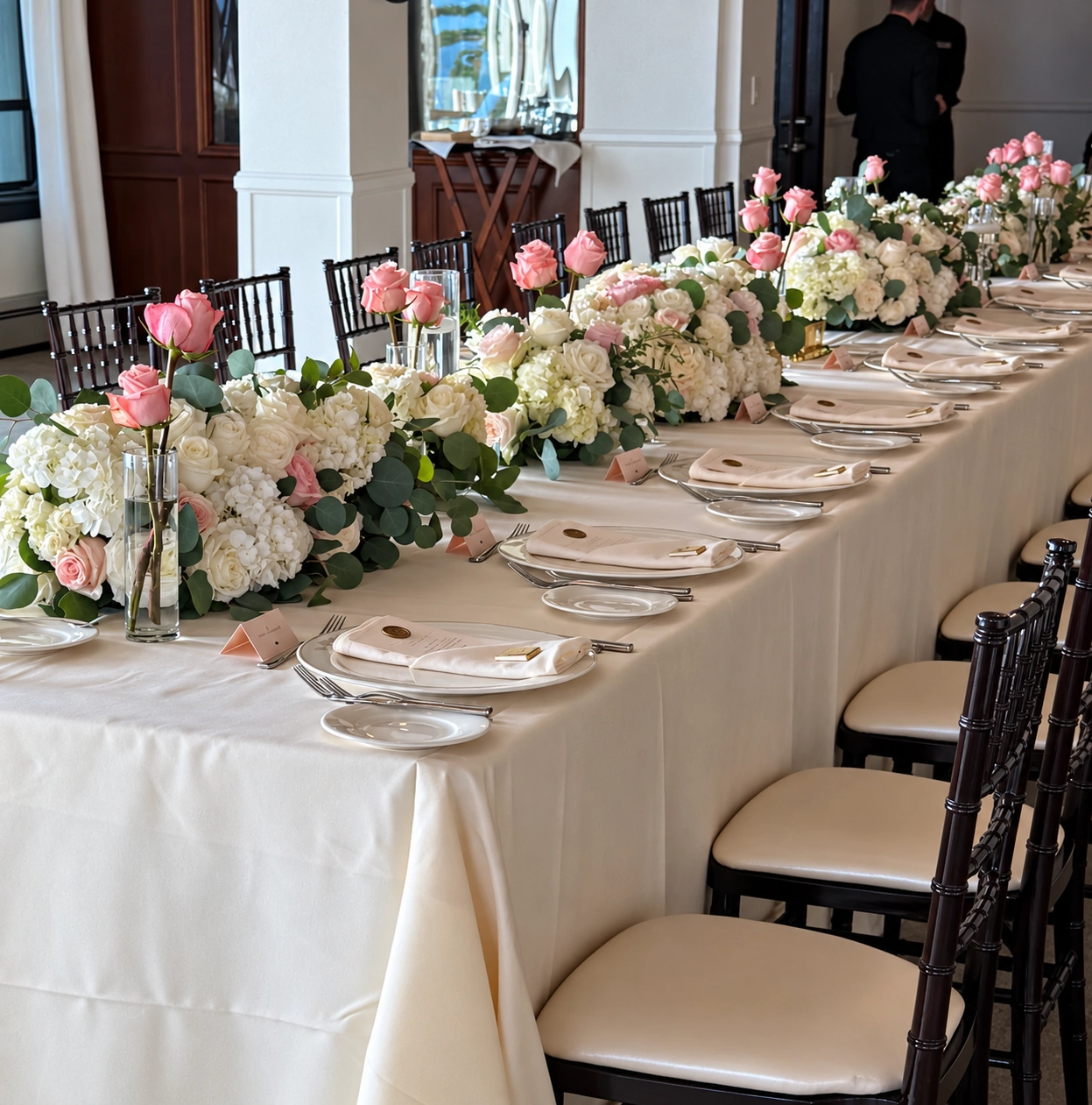 White hydrangeas, pink roses, and glass bud vases along a private dinner table